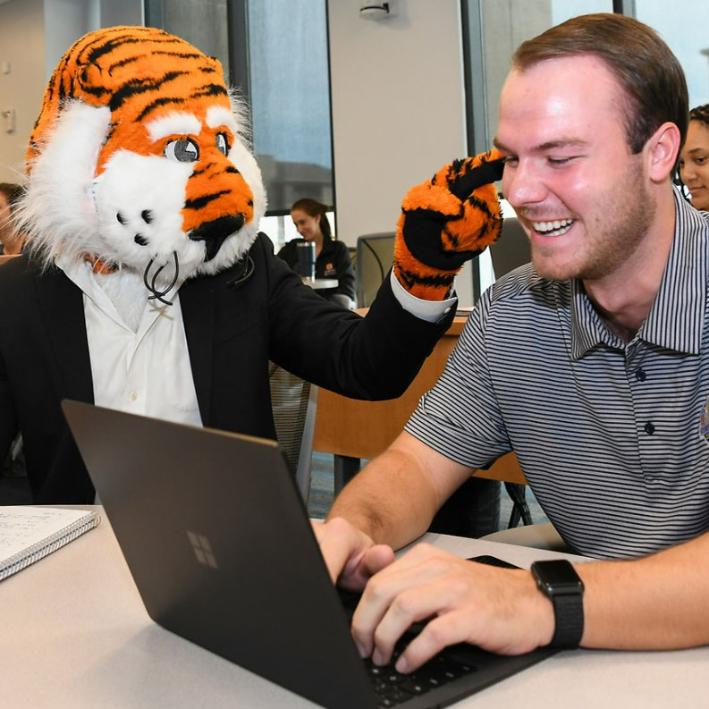 Aubie interacting with student at laptop